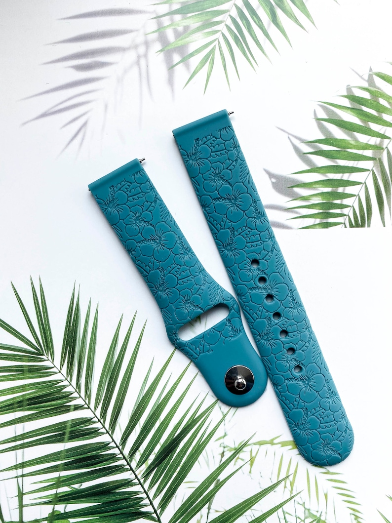 May include: Two teal blue silicone watch bands with a floral embossed pattern. The bands are designed for smartwatches.