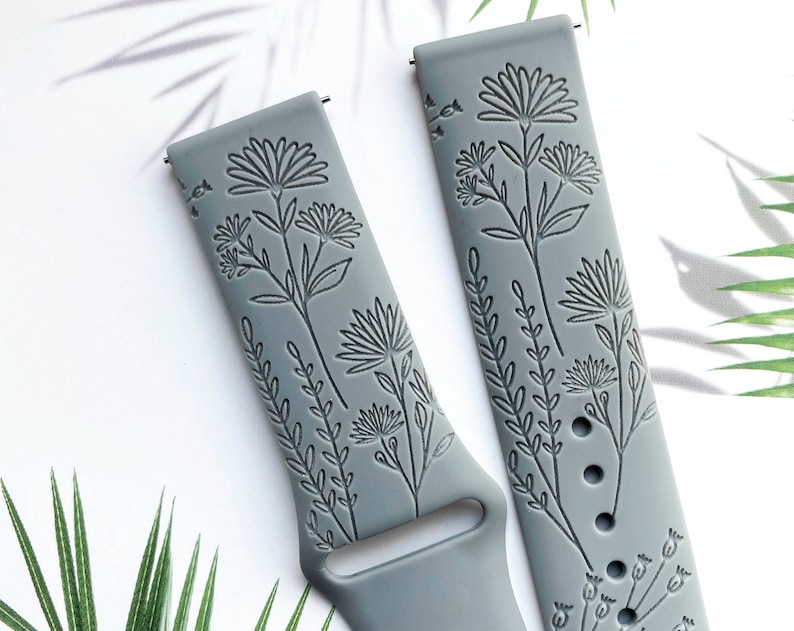 May include: Two gray silicone watch bands with a floral design. The bands have a raised floral pattern and are designed for smartwatches.