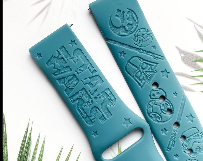K&ouml;nnte beinhalten: Zwei tealblaue Silikon-Uhrenarmb&auml;nder mit gepr&auml;gten Star Wars-Charakteren und den Worten "Star Wars" auf einem Armband. Die Charaktere sind Darth Vader, Yoda, R2-D2 und ein Stormtrooper.