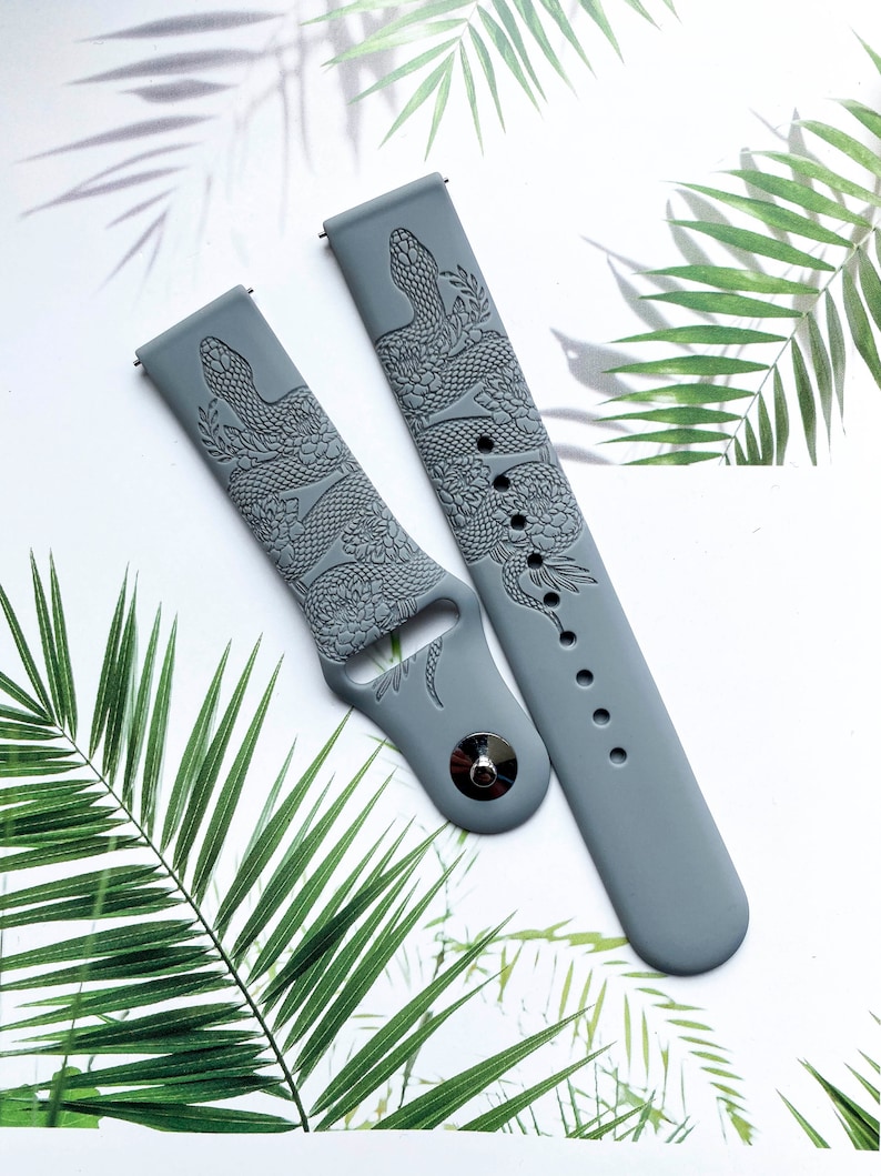 May include: Two gray silicone watch bands with a snake and floral design. The bands are embossed with a detailed pattern.