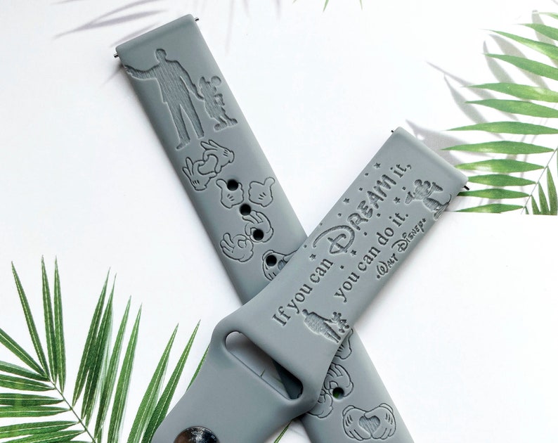 May include: Two grey silicone watch bands with a Disney theme. One band features Mickey Mouse icons and the other band features the quote "If you can dream it, you can do it." with a Mickey Mouse icon and the Disney logo.