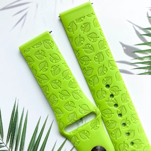 May include: Two lime green silicone watch bands with a repeating pattern of leaf designs. The bands are designed for smartwatches.