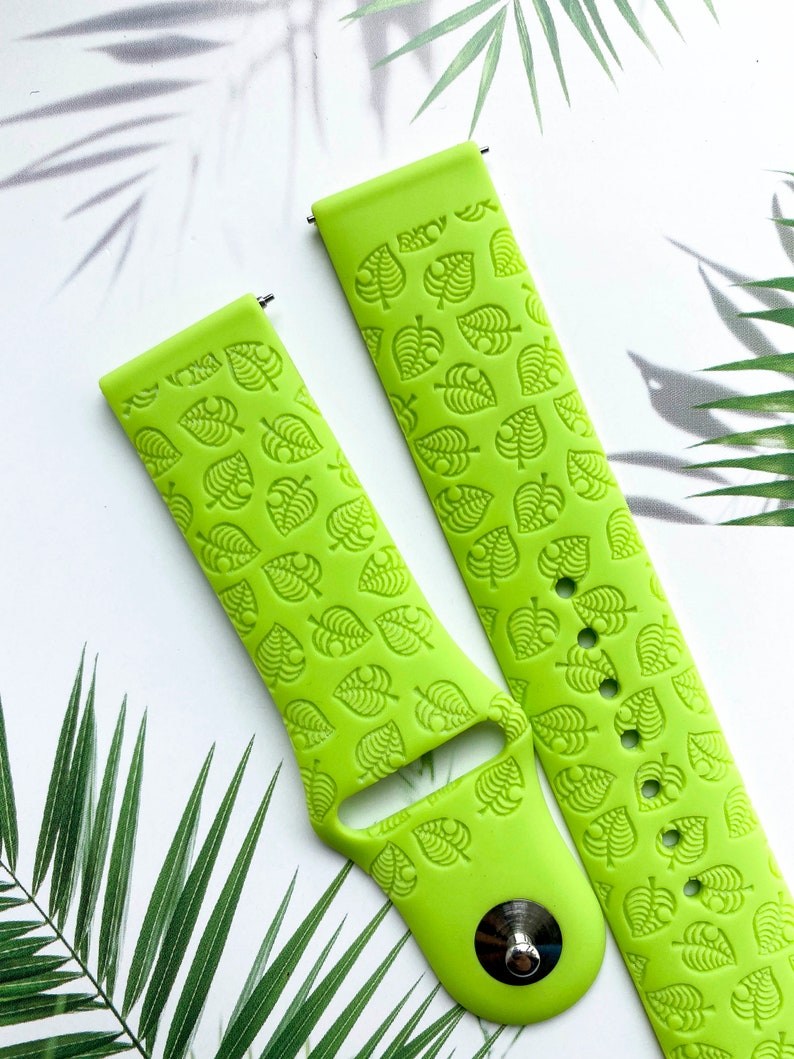 May include: Two lime green silicone watch bands with a repeating pattern of leaf designs. The bands are designed for smartwatches.