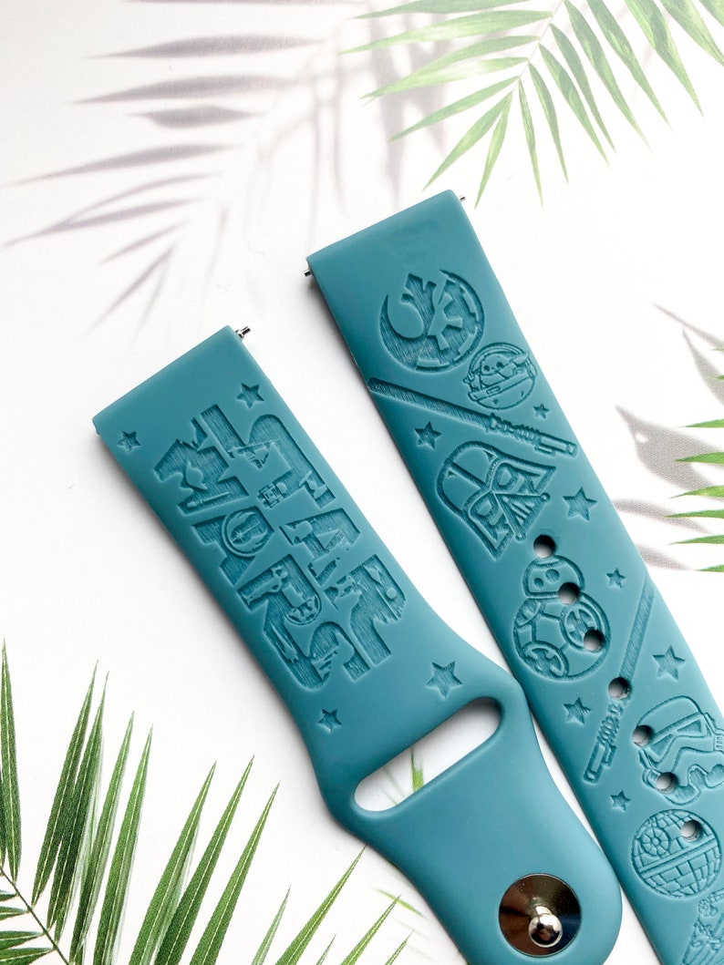 K&ouml;nnte beinhalten: Zwei tealblaue Silikon-Armb&auml;nder mit gepr&auml;gten Star Wars-Charakteren und dem Text "Star Wars".
