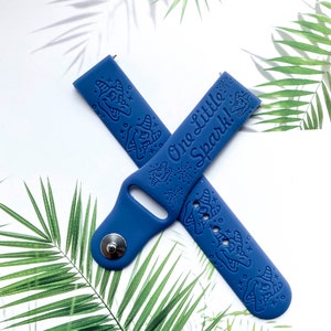May include: A blue silicone watch band with a white print of a unicorn and the text "One Little Spark!"