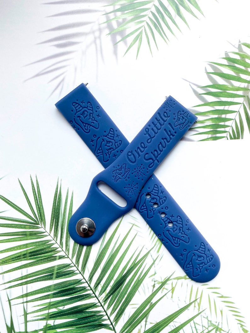 May include: A blue silicone watch band with a white print of a unicorn and the text "One Little Spark!"