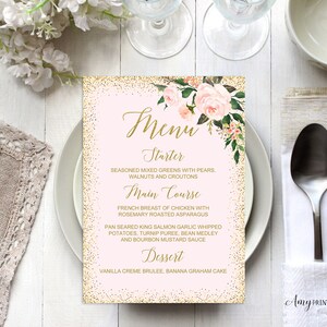 Puede incluir: Una tarjeta de menú de boda con fondo rosa y detalles de purpurina dorada. El menú presenta arreglos florales y una elegante escritura dorada. El menú incluye las opciones de entrante, plato principal y postre. También se ven cubiertos y un plato blanco.