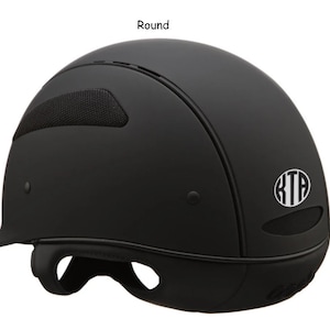May include: Black riding helmet with a round shape and a white monogram "KTA" on the side.