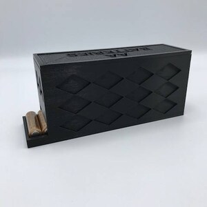 Puede incluir: Caja de almacenamiento de bater&iacute;as negra con un patr&oacute;n de diamantes y el texto "Sealed By" en la parte superior. La caja tiene un compartimento en la parte delantera para guardar bater&iacute;as.