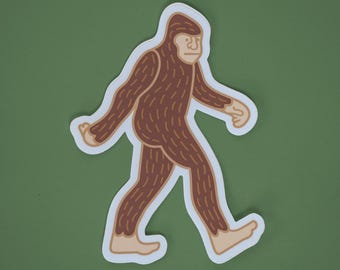 May include: A brown and white sticker of a cartoon Bigfoot walking. The Bigfoot is brown with a white face and has a white outline.