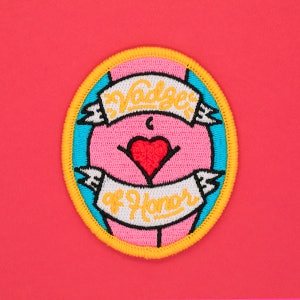May include: A yellow, blue, and pink embroidered patch with the text "Badge of Honor" and a red heart in the center.