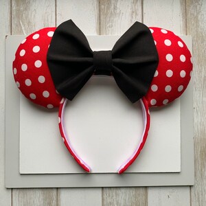 May include: Red and white polka dot Minnie Mouse ears headband with a black bow.