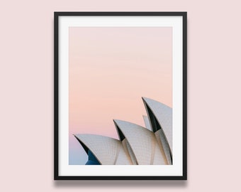 Może przedstawiać: Widok z bliska Opery w Sydney z różowo-pomarańczowym niebem w tle.