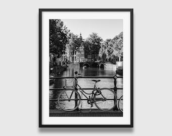 Impresión de una bicicleta en Ámsterdam: fotografía en blanco y negro de un canal, arquitectura holandesa