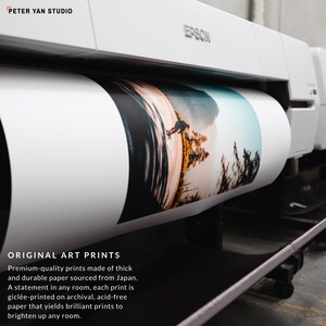 May include: A white Epson printer with a roll of paper printing a colorful landscape photograph. The text "ORIGINAL ART PRINTS" is visible below the printer. The text reads "Premium-quality prints made of thick and durable paper sourced from Japan. A statement in any room, each print is gicl&eacute;e-printed on archival, acid-free paper that yields brilliant prints to brighten up any room."