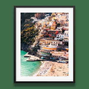 May include: A colorful, hillside town with buildings stacked on top of each other. The town is located on a cliff overlooking a sandy beach and turquoise water.