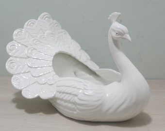 May include: White ceramic peacock planter with a detailed tail and a hollow body for planting.