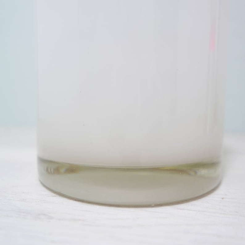 K&ouml;nnte beinhalten: Ein klares Glas-Kerzengef&auml;&szlig; mit wei&szlig;er, matter Oberfl&auml;che. Das Gef&auml;&szlig; hat einen dicken, abgerundeten Boden.