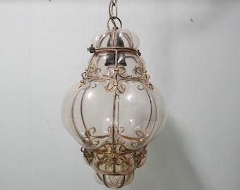 Puede incluir: Una lámpara colgante de vidrio transparente con un marco de metal dorado. El vidrio tiene forma de una serie de burbujas y el marco tiene un diseño decorativo.