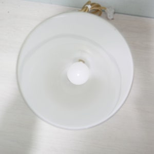 K&ouml;nnte beinhalten: Ein wei&szlig;er Lampenschirm mit einer wei&szlig;en Gl&uuml;hbirne im Inneren. Der Lampenschirm besteht aus einem glatten, undurchsichtigen Material.