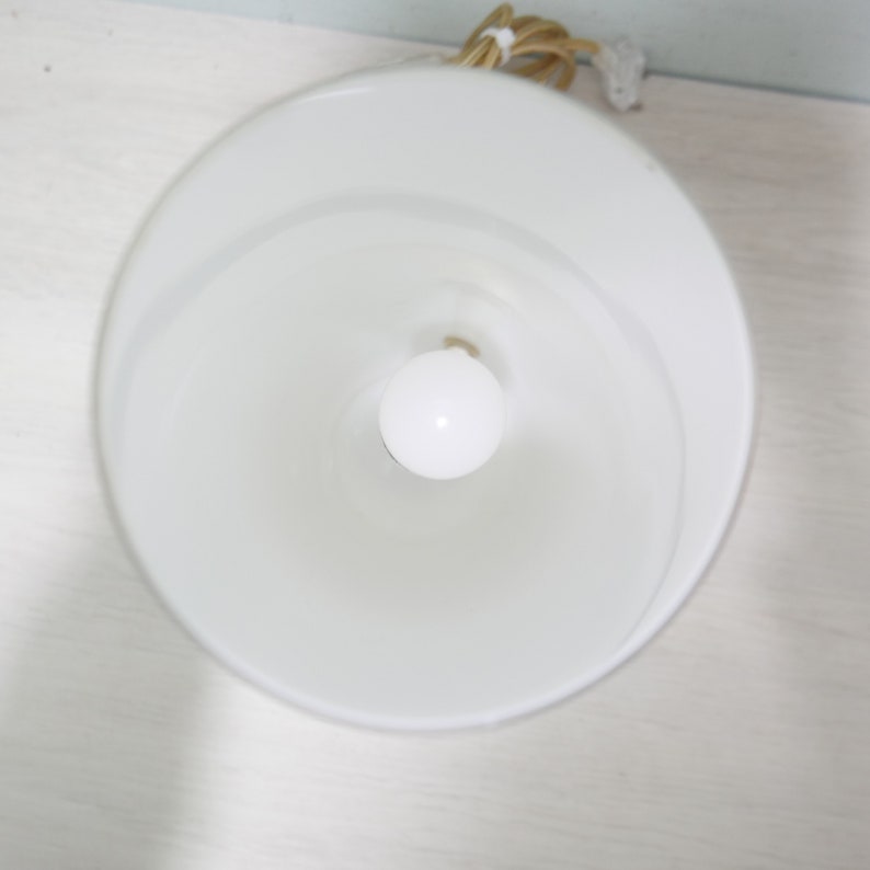K&ouml;nnte beinhalten: Ein wei&szlig;er Lampenschirm mit einer wei&szlig;en Gl&uuml;hbirne im Inneren. Der Lampenschirm besteht aus einem glatten, undurchsichtigen Material.