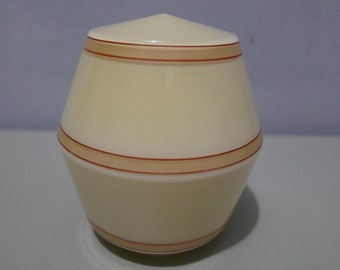 May include: A cream-colored ceramic jar with a rounded, slightly pointed top and a wide base. The jar has three thin, horizontal bands of orange and brown around the middle.