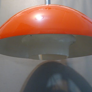 May include: Orange and white pendant light fixture with a dome-shaped shade.