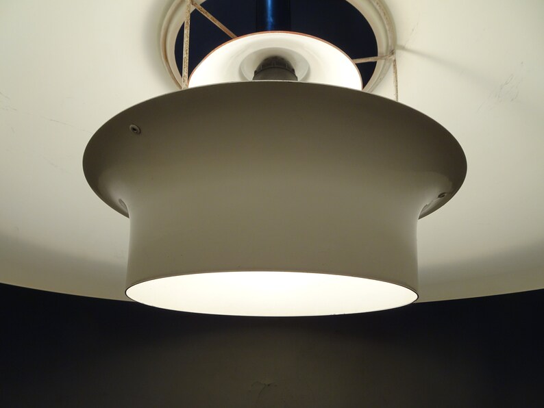 May include: A white ceiling light fixture with a round, white shade. The light is on and illuminating the room.