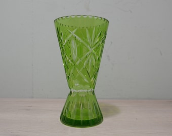 May include: A green glass vase with a cut glass design. The vase has a flared top and a wide base.