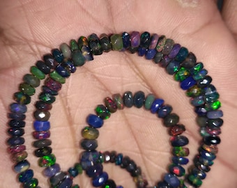 May include: A strand of black opal beads with iridescent colors, including green, blue, and red. The beads are faceted and have a variety of shapes and sizes.