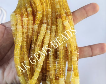 May include: A strand of yellow opal beads, each bead is faceted and has a slightly irregular shape. The beads are strung on a clear thread and are approximately 4mm in diameter. The beads are displayed on a hand, with the text "AK GEMS BEADS" visible in the background.