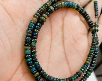 May include: A strand of dark green and black opal beads, strung on a thin cord. The beads are round and have a slightly iridescent sheen.