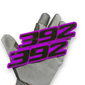 May include: A grey work glove with a black and purple graphic of the numbers "392" stacked. The numbers have a purple outline and are angled across the glove.