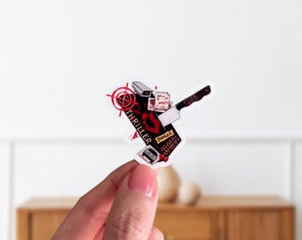 May include: A sticker with a thriller theme. The design includes a knife, a security camera, and the word "Thriller" in red. The word "Danger" is also visible. The sticker is held by a person.