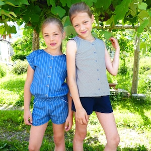 Peut inclure: Deux jeunes filles portant des tenues d'été. L'une porte une combinaison bleu et blanc à rayures avec des manches courtes et des boutons sur le devant. L'autre porte un chemisier gris sans manches à pois bleu et blanc et un short bleu foncé.