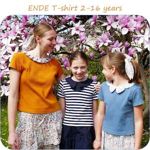 Puede incluir: Tres chicas con camisetas ENDE con cuellos florales. Las camisetas son de color mostaza, azul y a rayas. El texto "ENDE T-shirt 2-16 years" está en la parte superior. El fondo presenta un árbol con flores rosas.