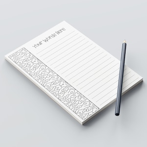 May include: A white notepad with lined pages and a decorative black and white cloud pattern border. The notepad has the text "Your Words Here" at the top. A gray pencil rests on the notepad.