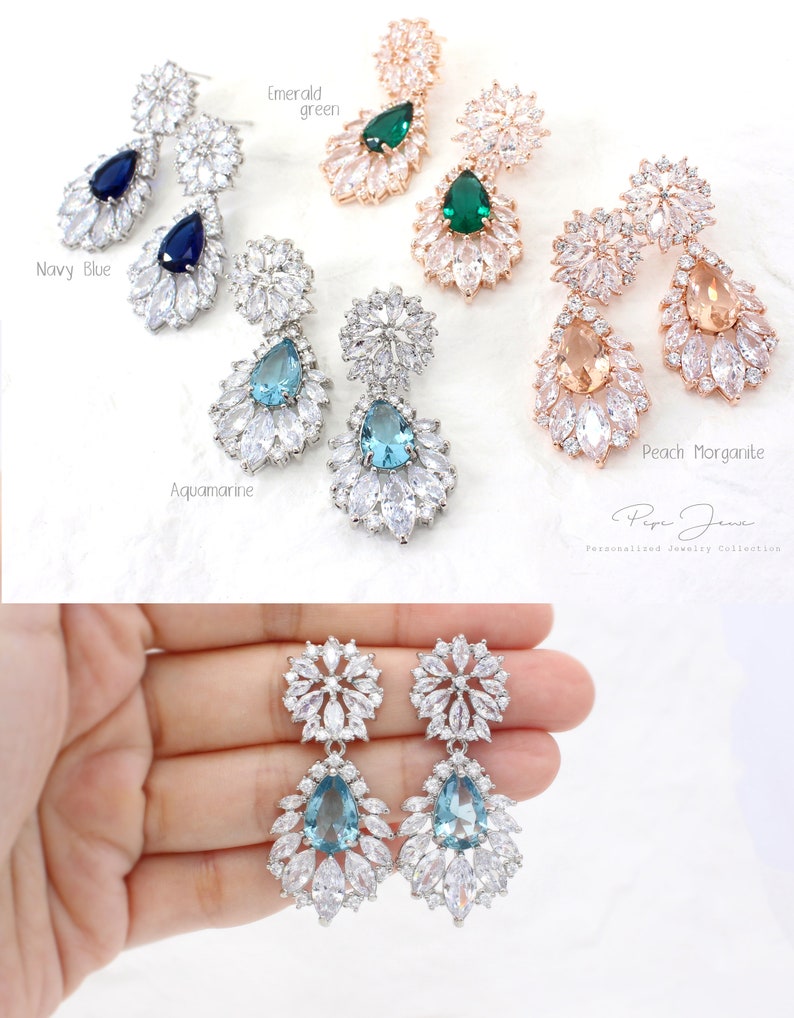 Puede incluir: Un par de pendientes de plata con forma de gota de agua azul y un racimo de piedras m&aacute;s peque&ntilde;as. Los pendientes se muestran en diferentes colores, incluyendo verde esmeralda, morganita melocot&oacute;n, aguamarina y azul marino.