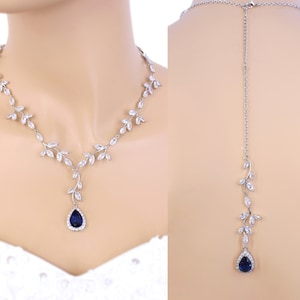 May include: A silver necklace with a teardrop-shaped blue gemstone pendant and a matching back necklace. The necklace features a delicate leaf design with clear crystals.