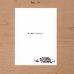 inside of card reads Merry Christmas!  There is a little illustration of a grey cat curled up on some wrapping paper in the bottom right corner of the card