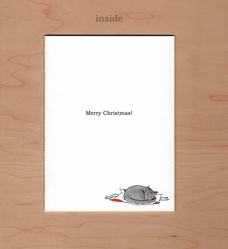 inside of card reads Merry Christmas!  There is a little illustration of a grey cat curled up on some wrapping paper in the bottom right corner of the card
