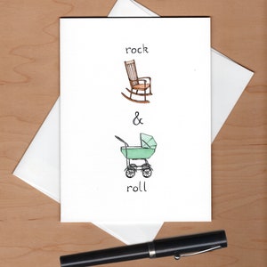 May include: A white card with a hand-drawn illustration of a rocking chair and a baby stroller. The text "rock & roll" is written below the illustrations.