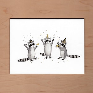 Peut inclure: Trois ratons laveurs portant des chapeaux de f&ecirc;te et tenant des cadeaux de f&ecirc;te. Les ratons laveurs sont debout sur un fond blanc avec des confettis dor&eacute;s qui tombent autour d'eux.