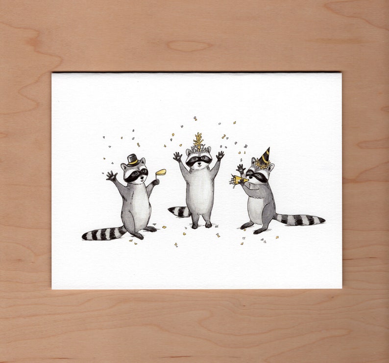 Peut inclure: Trois ratons laveurs portant des chapeaux de f&ecirc;te et tenant des cadeaux de f&ecirc;te. Les ratons laveurs sont debout sur un fond blanc avec des confettis dor&eacute;s qui tombent autour d'eux.