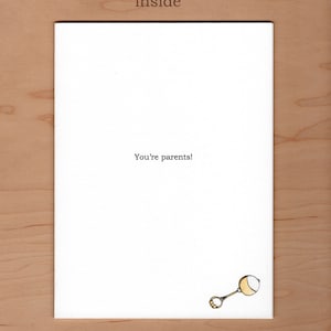 May include: A white card with the text "You're parents!" and a simple drawing of a rattle in the bottom right corner.