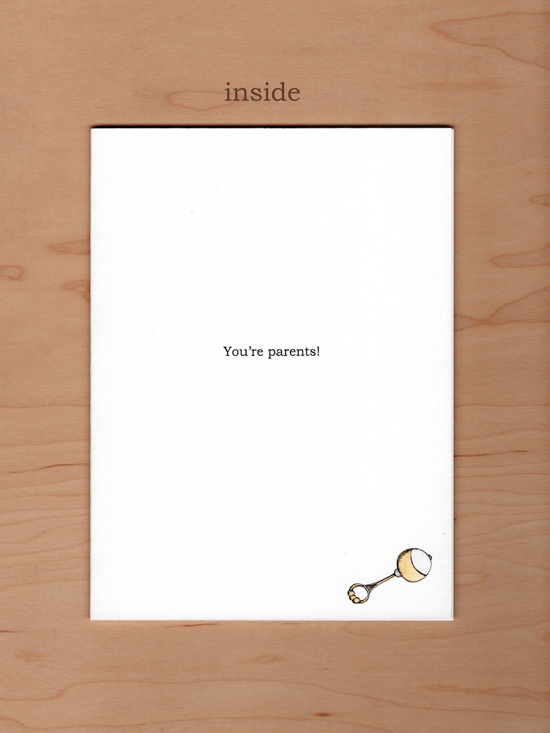 May include: A white card with the text "You're parents!" and a simple drawing of a rattle in the bottom right corner.