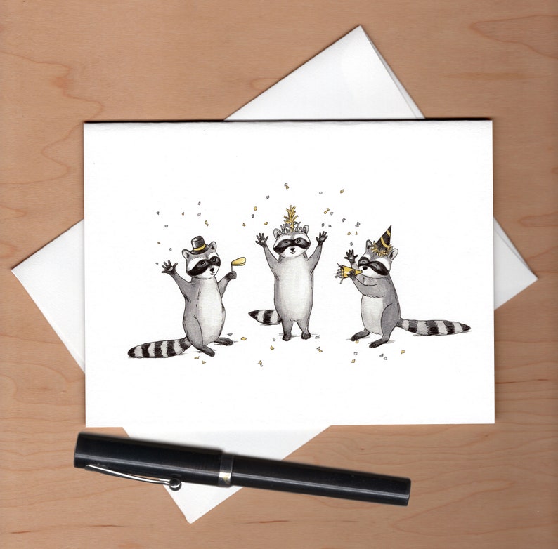 Peut inclure: Trois ratons laveurs portant des chapeaux de f&ecirc;te et tenant des cadeaux de f&ecirc;te. Les ratons laveurs sont debout en rang et sont entour&eacute;s de confettis. L'arri&egrave;re-plan est blanc.