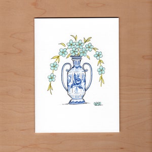 May include: A blue and white ceramic vase with a floral design and a bouquet of light blue flowers.