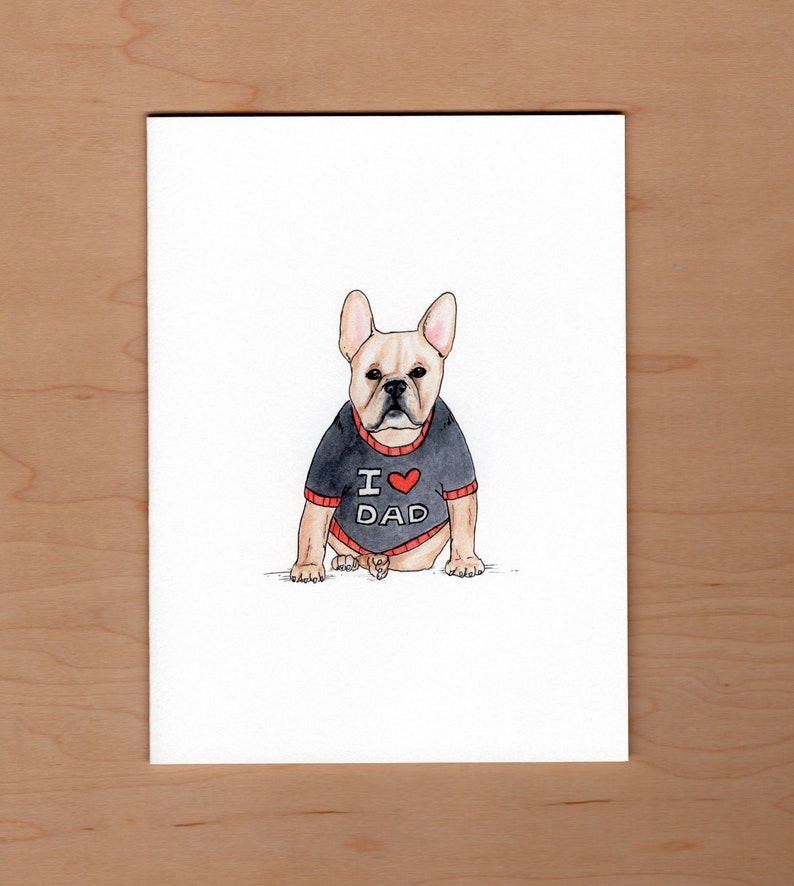 Pu&ograve; includere: Illustrazione ad acquerello di un bulldog francese con un maglione nero con finiture rosse. Il maglione ha la scritta "I ❤️ DAD" in lettere bianche con un cuore rosso. Il cane &egrave; marrone chiaro con il naso nero e si trova su uno sfondo bianco.