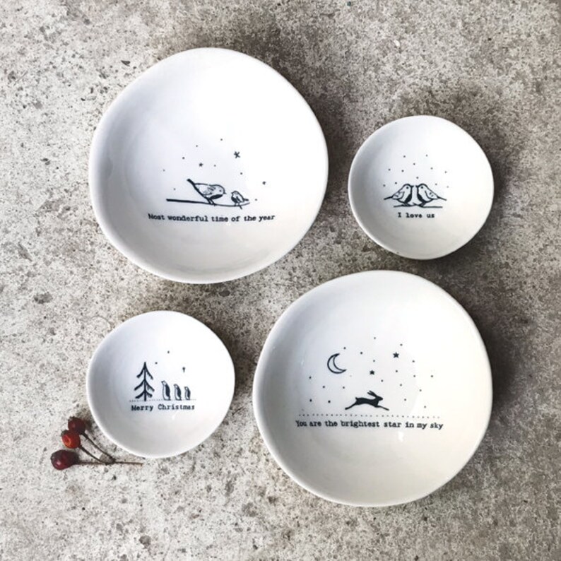Op de afbeelding: Set van vier witte keramische kommen met zwart-wit illustraties en tekst. De kommen bevatten de volgende tekst: "Most wonderful time of the year", "I love us", "Merry Christmas", en "You are the brightest star in my sky".